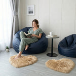 Pink heart shaped faux fur rug on a wood bedroom floor beside a bed