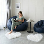 Pink heart shaped faux fur rug on a wood bedroom floor beside a bed