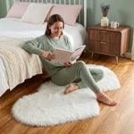 Pink heart shaped faux fur rug on a wood bedroom floor beside a bed