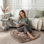 Pink heart shaped faux fur rug on a wood bedroom floor beside a bed