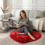 Pink heart shaped faux fur rug on a wood bedroom floor beside a bed