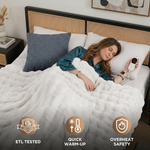 Woman sleeping in bed wrapped in the white heated throw with ETL tested, quick warm-up, and overheat safety icons