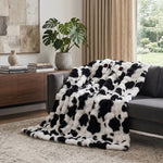 White faux rabbit fur heated blanket with bubble texture draped over a grey sofa in a modern living room