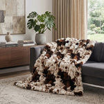 White faux rabbit fur heated blanket with bubble texture draped over a grey sofa in a modern living room