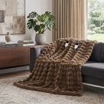 White faux rabbit fur heated blanket with bubble texture draped over a grey sofa in a modern living room