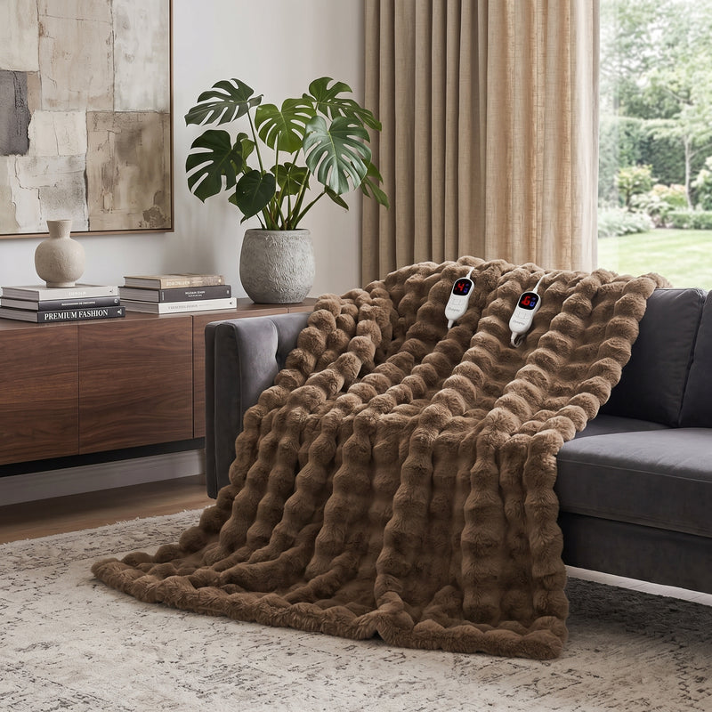 White faux rabbit fur heated blanket with bubble texture draped over a grey sofa in a modern living room