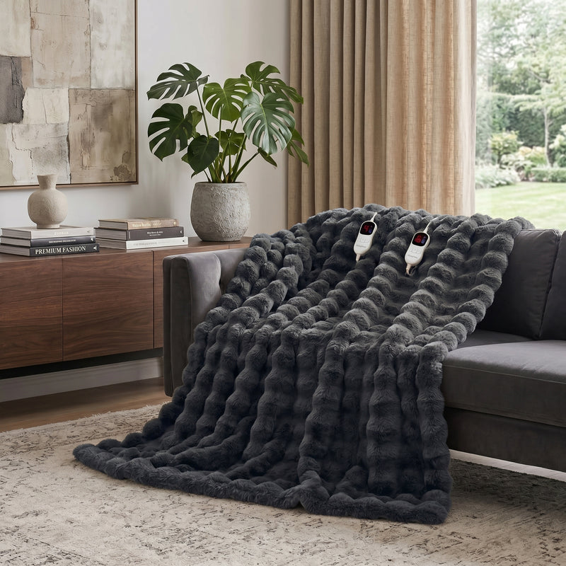 White faux rabbit fur heated blanket with bubble texture draped over a grey sofa in a modern living room