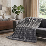 White faux rabbit fur heated blanket with bubble texture draped over a grey sofa in a modern living room