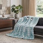 White faux rabbit fur heated blanket with bubble texture draped over a grey sofa in a modern living room