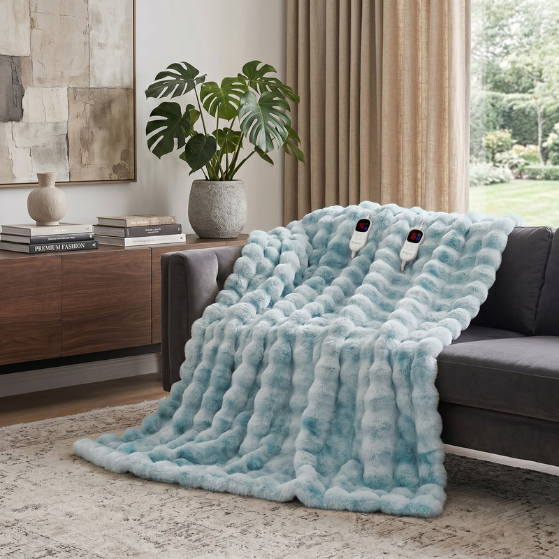 White faux rabbit fur heated blanket with bubble texture draped over a grey sofa in a modern living room