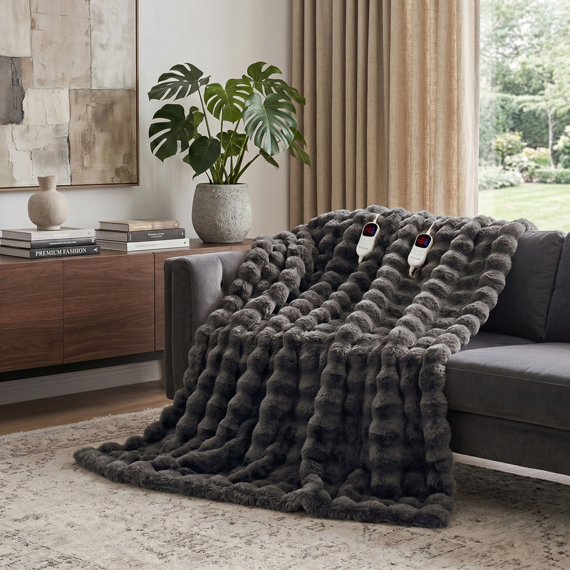White faux rabbit fur heated blanket with bubble texture draped over a grey sofa in a modern living room