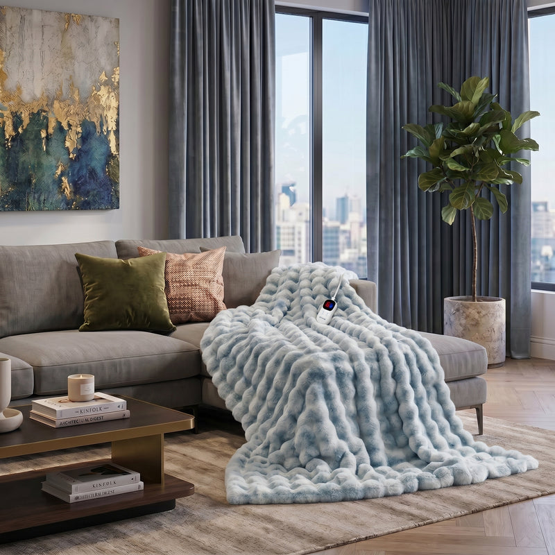 White faux rabbit fur heated blanket with bubble texture draped over a grey sofa in a modern living room