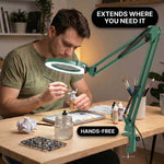 Man using a clamp-mounted LED magnifying lamp to hand-paint a miniature figure at a hobby desk