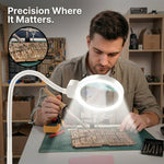 Man using a clamp-mounted LED magnifying lamp to hand-paint a miniature figure at a hobby desk