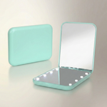 LED travel makeup mirror in pink, shown closed and open with LED lights on
