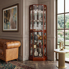 Oak lighted corner curio cabinet displaying crystal and glassware in a living-room corner