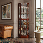 Oak lighted corner curio cabinet displaying crystal and glassware in a living-room corner