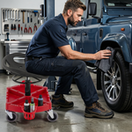 Person in grey coveralls sitting on the rolling mechanic stool while working on a car wheel