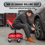 Person in grey coveralls sitting on the rolling mechanic stool while working on a car wheel
