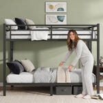 Adult standing beside a black metal bunk bed showing its full-size scale