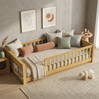 Natural wood Montessori floor bed with fence rails styled in a child's room