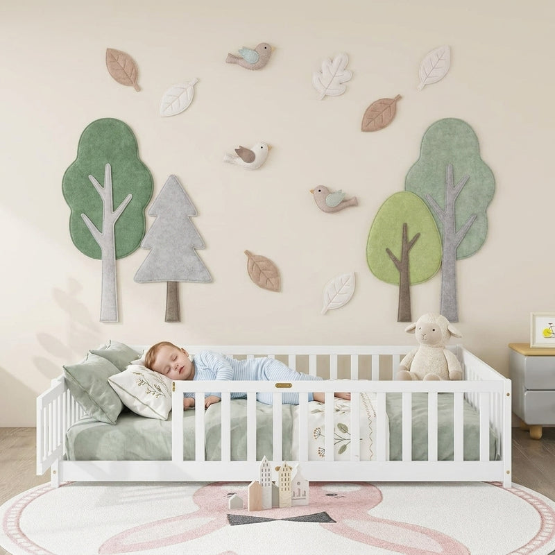 Toddler resting on a natural Montessori floor bed with fence in a forest-themed nursery