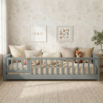 Toddler resting on a natural Montessori floor bed with fence in a forest-themed nursery