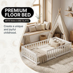 Toddler resting on a natural Montessori floor bed with fence in a forest-themed nursery