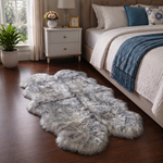 Real sheepskin rug in tan placed beside a bed on dark hardwood floor in a bedroom setting