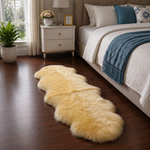 Real sheepskin rug in tan placed beside a bed on dark hardwood floor in a bedroom setting