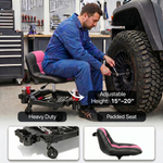 Mechanic seated on a red rolling garage stool adjusting a truck tire with a wrench