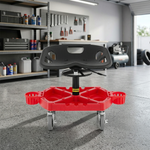Red and black padded rolling mechanic stool with a divided tool tray and five casters in a garage