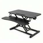 Black standing desk converter shown raised to standing height with keyboard tray