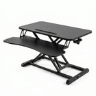 Black standing desk converter shown raised to standing height with keyboard tray