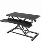 Black standing desk converter shown raised to standing height with keyboard tray