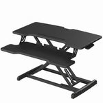 Black standing desk converter shown raised to standing height with keyboard tray extended
