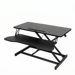 Black standing desk converter shown raised to standing height with keyboard tray extended