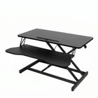 Black standing desk converter shown raised to standing height with keyboard tray