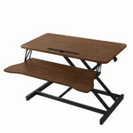 Black standing desk converter shown raised to standing height with keyboard tray extended