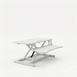 Black standing desk converter shown raised to standing height with keyboard tray