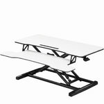 Black standing desk converter shown raised to standing height with keyboard tray extended