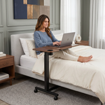 Overbed table with tilt top surface, laptop and coffee mug placed on top