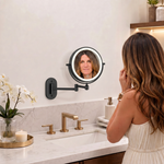 Woman adjusting a wall mounted LED magnifying makeup mirror in a bathroom vanity setting