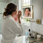 Woman using the wall-mounted makeup mirror at a bathroom vanity