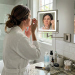 Woman using the wall-mounted makeup mirror at a bathroom vanity