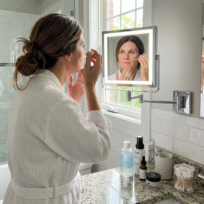 Woman using the wall-mounted makeup mirror at a bathroom vanity