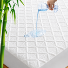 Quilted waterproof mattress protector on a bed in a bright bedroom