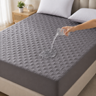 Quilted waterproof mattress protector on a bed in a bright bedroom