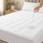 Quilted waterproof mattress protector on a bed in a bright bedroom