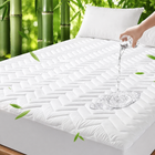 Quilted waterproof mattress protector on a bed in a bright bedroom